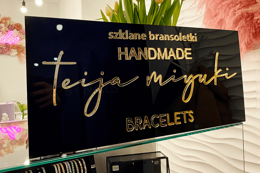 Szyld z czarnym tłem i złotymi literami na wymiar